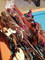 Photo showing wrapped artificial flower stems and leaf sprays in brown, white, and purple tones on a table.