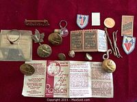 Lot arranged on red cloth including 1943 Montreal transit tickets, multiple military buttons, ring in packaging, pins, Ronson lighter paper, and penny for size comparison.