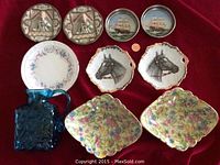 Lot of four pairs of decorative plates and a small cobalt blue glass pitcher, items arranged on red cloth, front view.