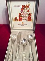 Full view of cutlery set in original box with illustrated lid showing teddy bears cooking, four pieces individually wrapped in plastic.