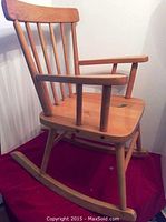 Side view of the child's wooden rocking chair showing spindle back, armrests and rocker base