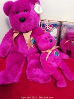 Front view of the Millennium 2000 purple bears in large and small sizes showing gold ribbons, black noses, and peacock feather emblem on chest.