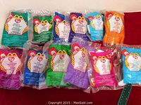 Photo showing 12 McDonald's Ty Teenie Beanie Babies still sealed in their original bags, arranged flat with visible Ty logo and McDonald's branding on packaging.