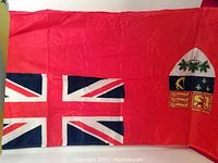 Full view of the Canadian Red Ensign flag showing the red background, Union Jack canton, and shield emblem.