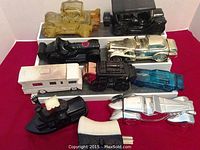 Full view of all 10 Avon vehicle bottles arranged on a white stand with red background, showing varied colors and vehicle types