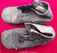 Top view of the pair of old child's shoes showing worn leather uppers and empty lace eyelets.