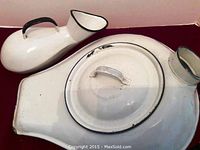 Wide shot of white porcelain urinal and bed pan with lid on red surface