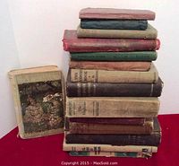 Stack of various old hardcover books in different colors, frayed edges and visible wear indicating age and use.