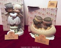 Front view of two Precious Moments figurines with original tags and boxes: angel couple and children in canoe.