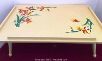 Front view of wooden breakfast tray with floral handpainted design on cream surface and folded legs extended.