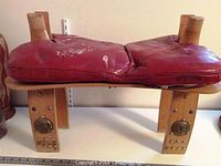 Top and side view of the burgundy leather cushion on the wooden folding seat frame showing some wear, loose stitching, and paint marks.