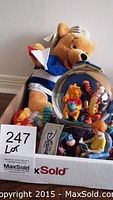 Box containing the stuffed Winnie the Pooh, musical globe, and hat box taken from a distance showing all items in the lot