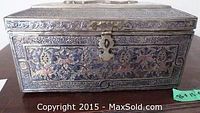 Closed decorative box showing engraved metal overlay and latch