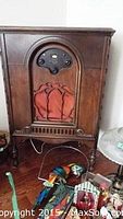Full front view of Atwater Kent antique radio in wooden cabinet showing grille fabric and carved legs.