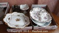 Photo showing a Limoges pedestal dish with floral and gold details, and a Johnson Bros platter stacked underneath a German segmented dish and platter.
