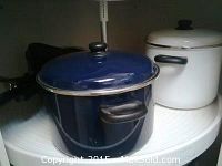 Blue enamel pot with lid and black handles alongside large white enamel roaster with black handles and lid knob