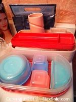 Photo showing several red and white storage containers with blue lids and small plastic boxes inside