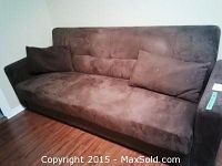 Full view of the brown studio couch with two matching cushions, showing overall shape and upholstery texture.