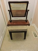 Victorian swing back dresser mirror on wooden base paired with a beige cushioned bench below it.