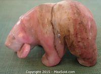 Front and side views of a small rhodonite bear figure holding a fish, showing detailed carving and natural stone color and veining.