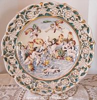 Front view of the Capodimonte platter showing the hand-painted and embossed cherubs, nudes, centaur, fish, and floral openwork border.
