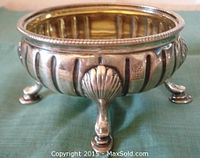 Side view of the sterling silver open salt dish showing fluted body and three shell-shaped feet, with visible hallmarks on the side.