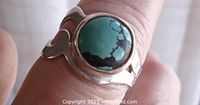 Close-up view of round turquoise cabochon stone set in polished sterling silver ring band.