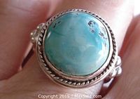 Close-up view of the ring top showing the round turquoise cabochon with bezel set double twisted silver frame.