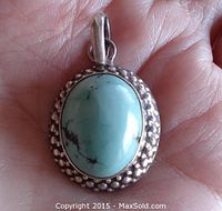 Top view of the turquoise pendant showing the oval cabochon and silver textured frame.