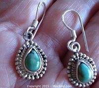 Close-up front view of both earrings showing teardrop turquoise stones surrounded by beaded sterling silver frames and fishhook earring wires.