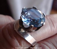 Close-up view of the sterling silver ring with large blue facetted stone held by prongs, showing detailed stone cuts and band.
