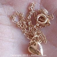 Close-up photo of the yellow gold chain and heart pendant held in hand, showing chain links and pendant shape.