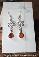 Pair of sterling silver Celtic style dangly earrings with amber stone drops shown on white card.