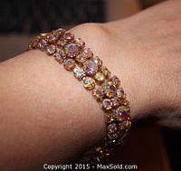 Close-up photo of the bracelet on a wrist showing multicolored pink Aurora Borealis rhinestones set in three rows.