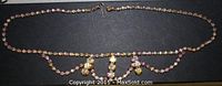 Full length view of the 17-inch pink aurora borealis rhinestone necklace with hooked clasp and swag design on gold-tone setting.