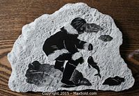 Front view of the carved soapstone slab showing an Eskimo catching a fish in black carving detail and signature "Dano".
