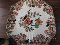 Top-down view of one square serving plate with a white background and a vibrant Imari floral pattern with orange and red flowers, green leaves, and gold trim scalloped edges.
