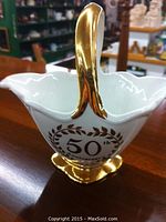 Angle showing front side with '50th Anniversary' emblem and gold handle and base