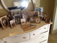 Photo of assortment of framed vintage photos on a dresser including portraits and military photos