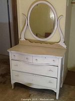 Front view of dresser and attached oval mirror showing overall shape and finish