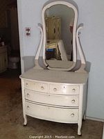 Front view of the white 4 drawer dresser with attached mirror showing overall shape, drawer knobs, and curved legs.
