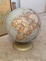Photo of the world globe showing continent details and gold-colored round base.