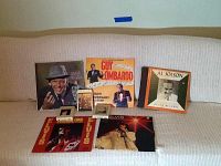 Group photo of 6 vinyl albums and 2 cassette tapes on white couch, showing full album cover art and cassette cases