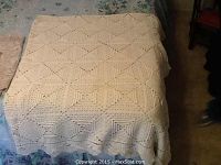 Queen crochet coverlet cream color with repeating square motifs, laid flat on bed