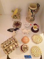 Photo of German beer stein with detailed handle, marked Germany, and assorted small decorative curios including ceramic animals, flower decor, and shell art