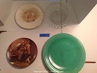 Four collector plates: green Genuine Fiesta plate, Norman Rockwell depiction plate, clear Fostoria Crystal plate, floral Taylor, Smith & Taylor plate.