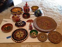 Full view of assortment on table, showing various wooden dishes, bowls, trays, and decorative item with colorful Russian folk art styles.