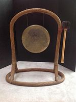 Front view of the full gong setup showing the woven stand holding the metal gong with mallet attached.