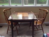 Game table with two matching chairs displayed near window, shows overall setup and condition.