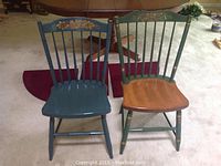 Photo showing two Hitchcock chairs on carpet with one painted green with natural seat, the other blue completely painted.